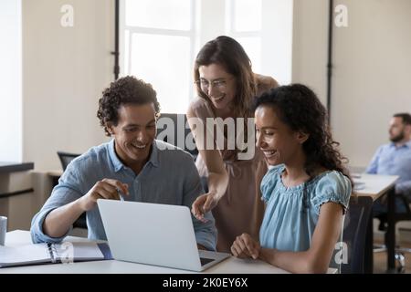 Happy cheerful startup team working at laptop computer together Stock Photo