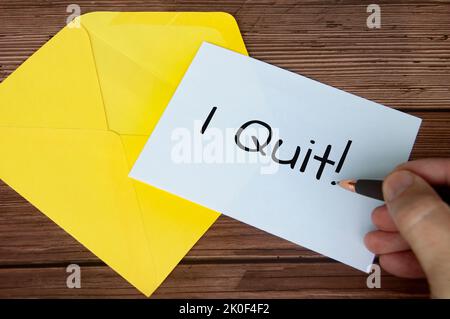 Hand writing I quit text on white notepad with yellow envelope background. Employment concept. Stock Photo