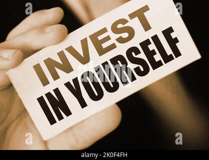 Invest in Yourself message on business card shown by a businessman. Education importance concept Stock Photo
