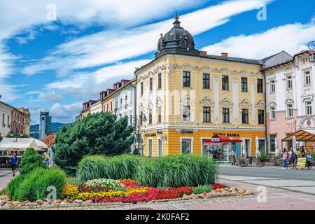 Banska Bystrica, Slovakia - August 17, 2021: view of SNP Square - colorful historic buildings, blooming flowers, green trees and people walking around Stock Photo