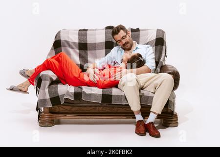 Portrait of loving couple sitting on sofa and talking, woman lying on man's knees Stock Photo