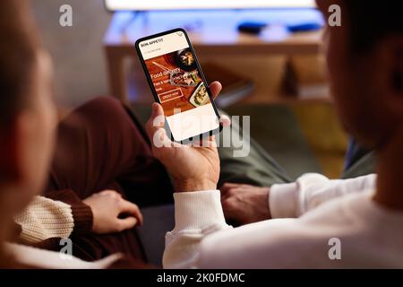 Close-up of young couple ordering food online on mobile phone while sitting at home Stock Photo