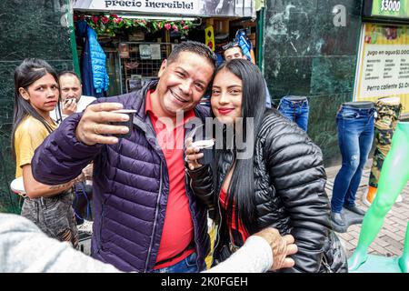 Bogota Colombia,San Victorino Carrera 10,coffee vendor smiling couple drinking cinnamon tea,man men male woman women female,Colombian Colombians Hispa Stock Photo
