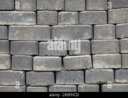 The surface of a wall or fence lined with gray bricks. Paving slabs of grey blocks of flat shape. Pavement blocks in city park. Park way materials Stock Photo