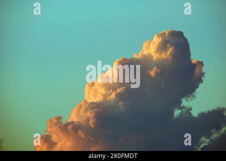 White fluffy cumulonimbus clouds forming before thunderstorm on evening sky. Changing stormy cloudscape weather at sunset Stock Photo