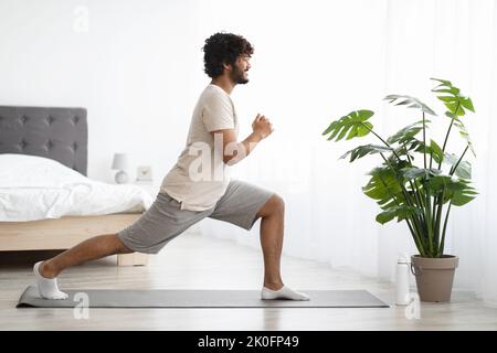 Sporty hindu guy doing workout at home, copy space Stock Photo