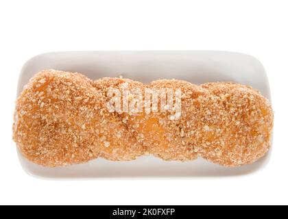 Top view flat lay of one cinnamon crumb coated glazed twist donut on a rectangular off white porcelain plate, isolated on white Stock Photo