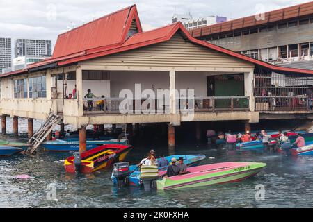 Kota Kinabalu, Malaysia - March 23, 2019: Motorboats with crew and passengers are moored at KK Fish Market on a sunny day, cheap public transport betw Stock Photo