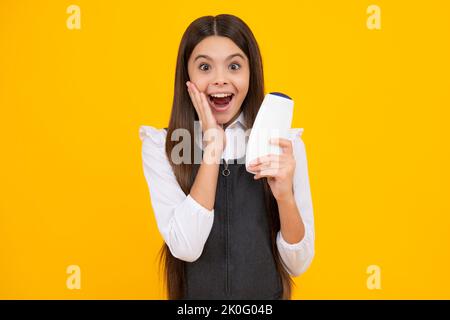 Amazed teen girl. Teenage girl with shampoos conditioners or shower gel. Kids hair care cosmetic product, shampoo bottle. Excited expression, cheerful Stock Photo