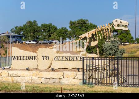 Roadside Welcome to Glendive sign with metal sculpture of a dinosaur in Glendive, Montana.  The sculptures is a tribute to the many dinosaurs bones fo Stock Photo