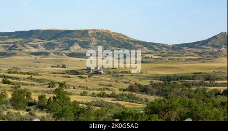 Evening light on a rural landscape with buttes and ranch or farm buildings near the Little Missouri National Grassland in Western North Dakota Stock Photo