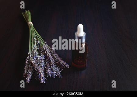 glass jar of lavender oil with fresh lavender flowers on black background. Stock Photo