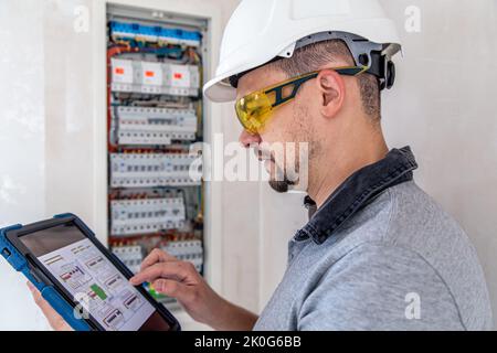 Electrical technician looking focused while working in a switchboard with fuses. Stock Photo
