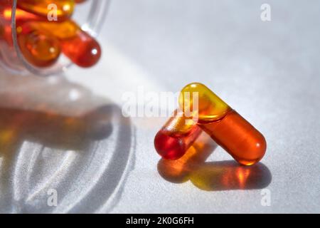 Curcumin in liquid form. Herbal capsules, herb turmeric capsules on neutral background with palm leaf shadow. Herbal medicine extract from turmeric Stock Photo