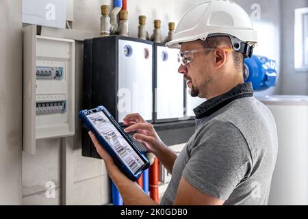 Electrical technician looking focused while working in a switchboard with fuses. Stock Photo