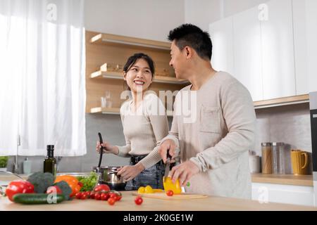 Positive japanese husband and wife making dinner together Stock Photo