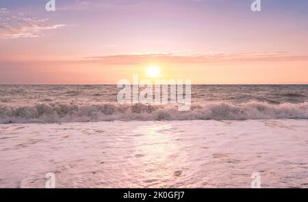 Sea splashing waves backlit by setting sun in front of beautiful sunset sky background. Travel and tourism concept. Nature background. Great wallpaper design. Copy space. Stock Photo