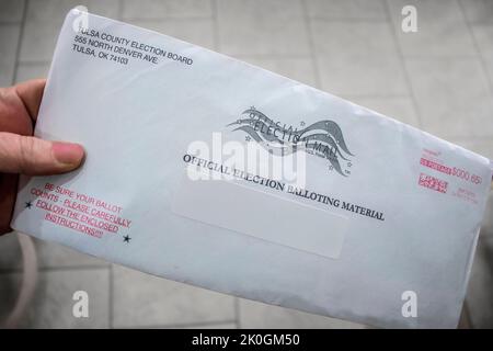 2020 10 02 Tulsa OK. Hand holding official Election Mail-in Ballot just received with blurred tile floor in background Stock Photo