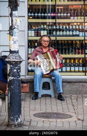 July 15 Tbilisi Georgia - Man sitting on stool in front of wine store playing accordion in Old Town Stock Photo