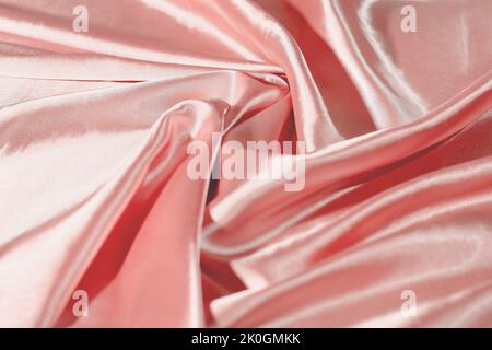 Top view of circular spiral fabric, pink satin fabric, peach shade cloth background, Spiral swirl fabric, swirl cloth, Twisted background, twisted clo Stock Photo