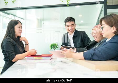 Friendly colleagues work team working together, laughing with positive emotions in the office. Stock Photo