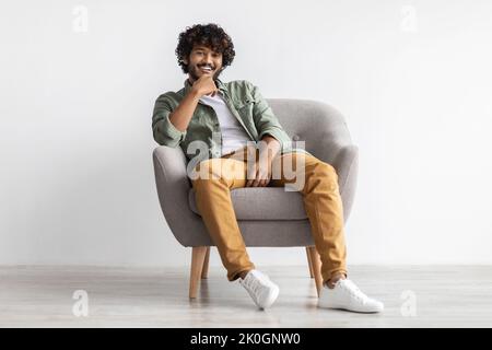 Relaxed indian guy chilling in arm chair over white background Stock Photo