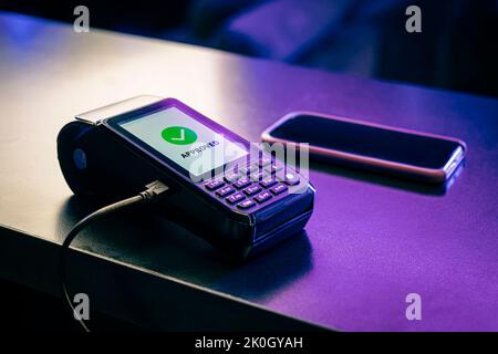 POS terminal, Payment Machine with mobile phone on dark background. Contactless payment with NFC technology. Payment approved. modern contactless paym Stock Photo