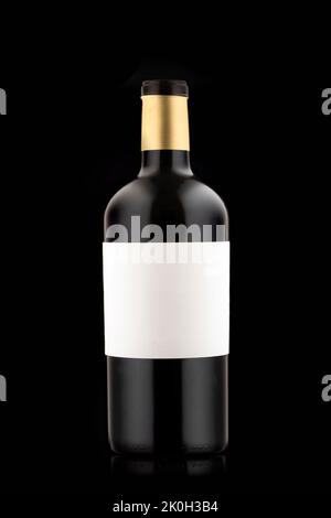 a small full bottle of beer or wine on a black background, with a blank white label. Stock Photo