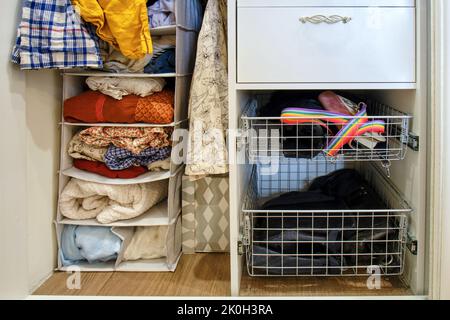 Open closet with women in the shelf, female dresses and shirts in the wardrobe Stock Photo