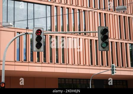 Two traffic lights showing a red light for cars turning left and green for driving straight down the street Stock Photo
