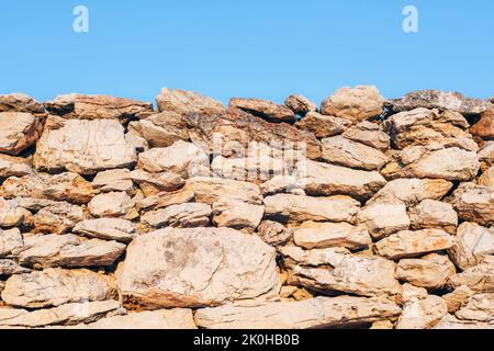 Old masonry stone wall and blue sky background, texture. Stock Photo