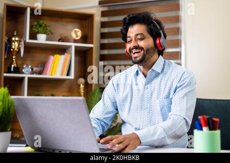 Happy businessman on online client meeting at office using laptop - concept of successful career, entrepreneur and executive. Stock Photo