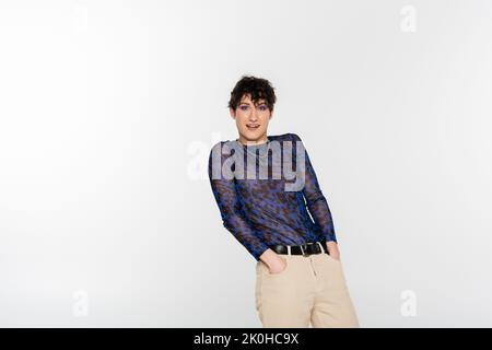 stylish queer person holding hands in pockets and looking at camera isolated on grey,stock image Stock Photo