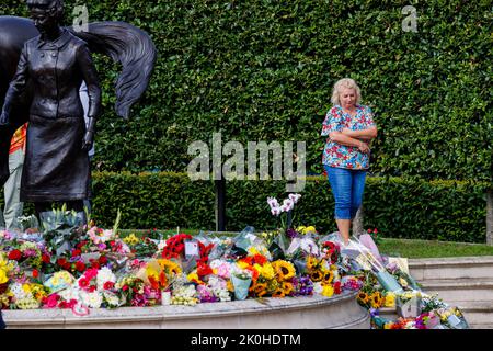 Newmarket, UK. 11 September, 2022.   Floral tributes left in memory to Queen Elizabeth II after her death on 8th September on a bronze statue designed by Etienne Millner, which is situated at the Newmarket Racecourse entrance which was a gift from the town in the year of her 90th birthday.  Credit: Mark Bullimore/Alamy Live News Stock Photo