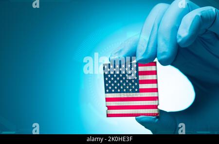 Electronic engineer hand holding computer chip with American flag on blue background. Chipset of electronic circuit board. CPU chip. Computer hardware Stock Photo