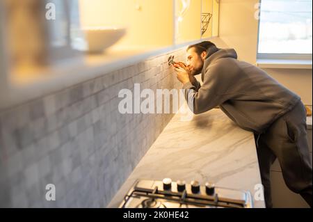 Man installing the power socket on the kitchen wall Stock Photo