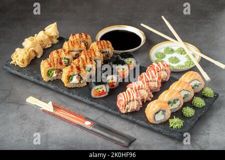 Sushi set of various products on a black stone plate. Blur background and selective focus Stock Photo