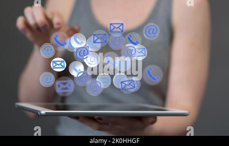 A woman holding a tablet with 3D rendered email and call icons hologram floating on the screen Stock Photo