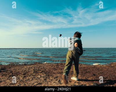 A little child throwing a stone into the sea Stock Photo