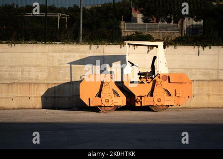 An asphalt paving machine with prominent shadow cast on the wall behind Stock Photo
