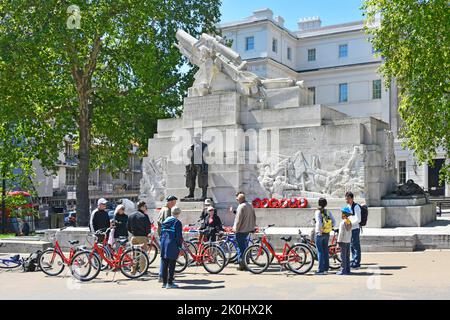 Tour guide on conducted guided tour group of men & women tourists hired bikes sightseeing Royal Artillery memorial Hyde Park Corner London England UK Stock Photo