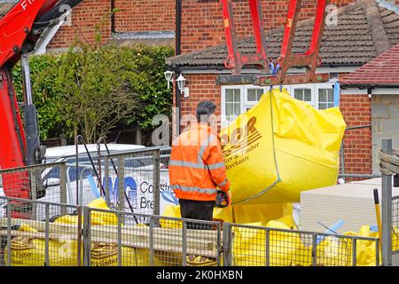 Close up builders merchant lorry truck mounted hydraulic crane back of delivery driver lifts jumbo bag building construction site materials England UK Stock Photo