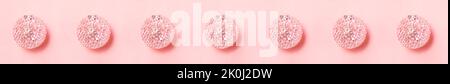 Christmas wide banner of row of pink textured Christmas balls on pastel pink background. Stripe with Xmas decorations. Festive image. Christmas or New Stock Photo