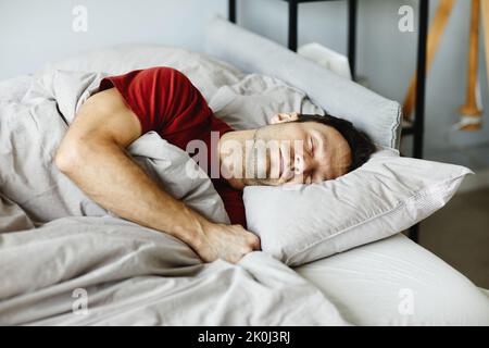 Mature man lying on pillow under blanket and sleeping in his bed in bedroom Stock Photo