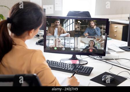 Over shoulder view of asian businesswoman making video call with diverse colleagues on screen. Business communication, working remotely and digital in Stock Photo