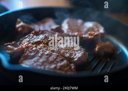 Beef steak with pepper is fried in a pan. Stock Photo