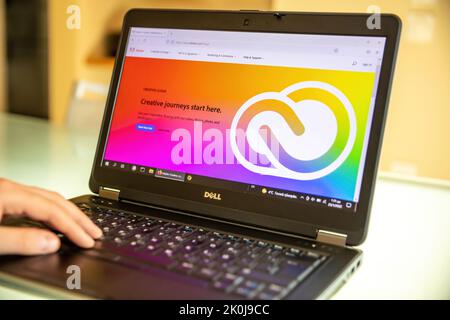 Greece, Athens, January 23 2022. ADOBE app. Creative Apps and Services company logo on laptop screen, blur office desk, hand on keyboard. Stock Photo