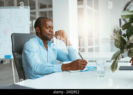 Confident African businessman taking notes while sitting in modern office Stock Photo