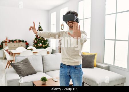 Young hispanic man smiling happy using 3d vr glasses at home. Stock Photo