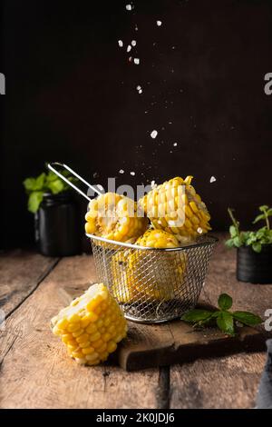 boiled corn cob. with salt and spices. vertical image. for advertising and menus. on a dark background Stock Photo